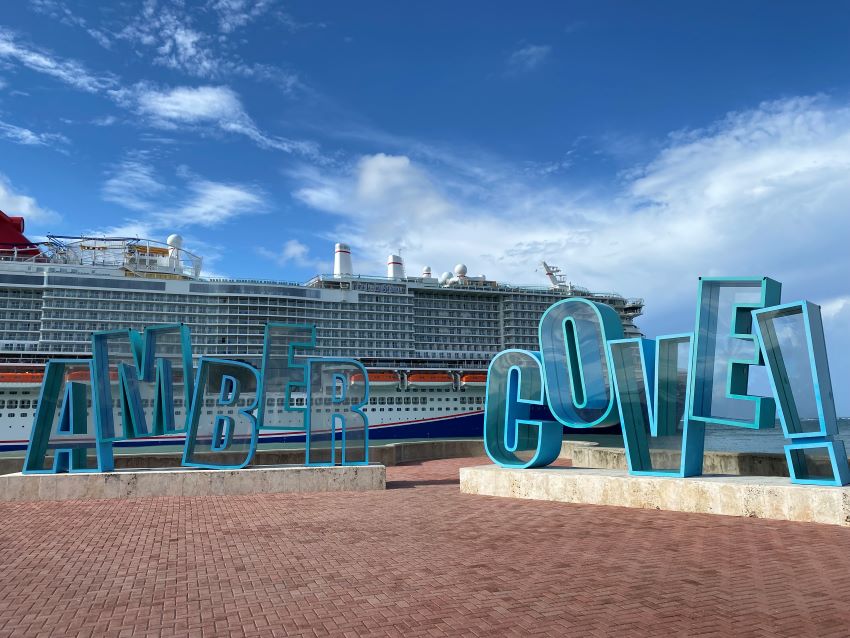 Amber Cove sign with a ship behind it.