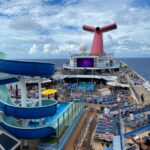 Carnival Quietly Makes a Drink Package Change That Means Longer Wait Between Servings Carnival Conquest pool deck with a blue sky