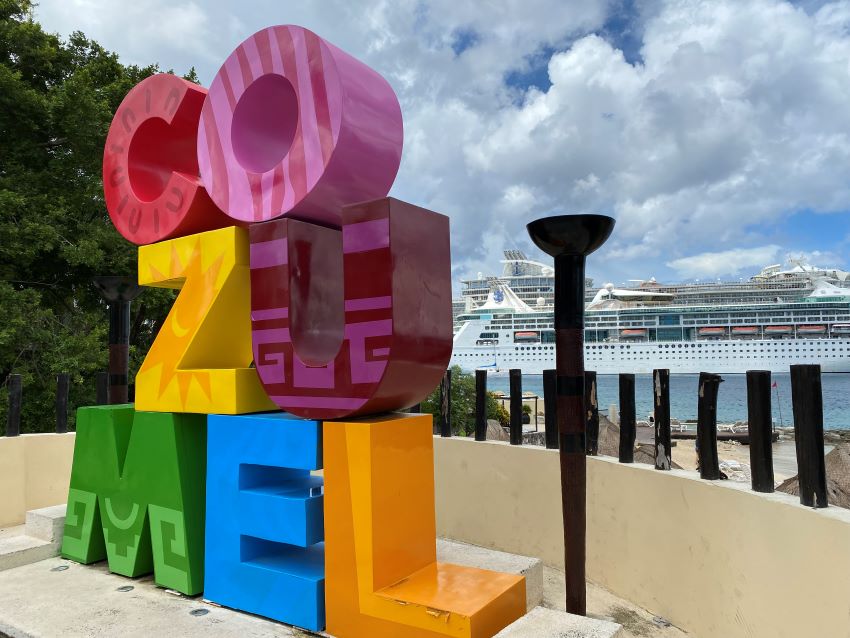 Colorful Cozumel sign with cruise ships in the background.